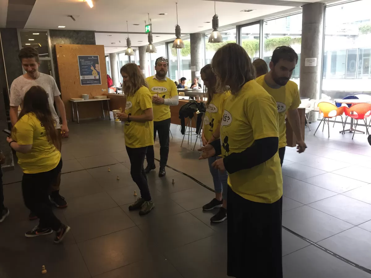 Multiple people participating on the yellow team wearing Světluška shirt with a view of the lobby and atrium in the background