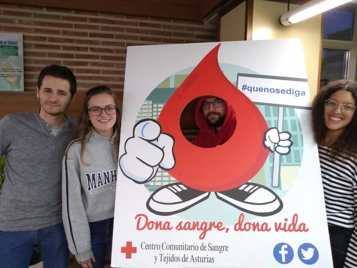 Four young people pose with a paper cutout of a blood-droplet-person.