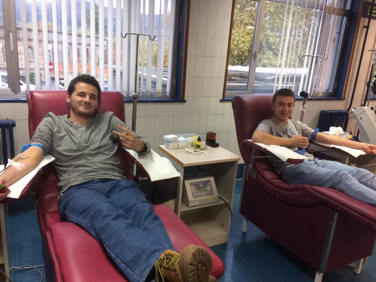 Two young people are sitting and donating blood.