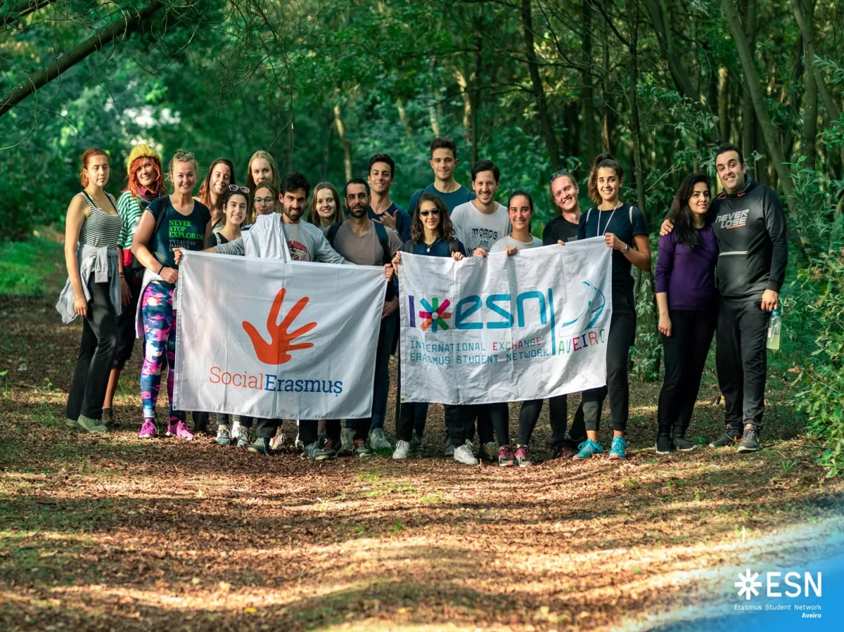 Group picture with all the participants, in the forest. The ones in the front row are holding the ESN Aveiro flag and the Social Erasmus flag. 