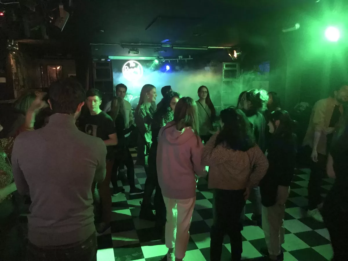 Image displays students socialising in a bar. 