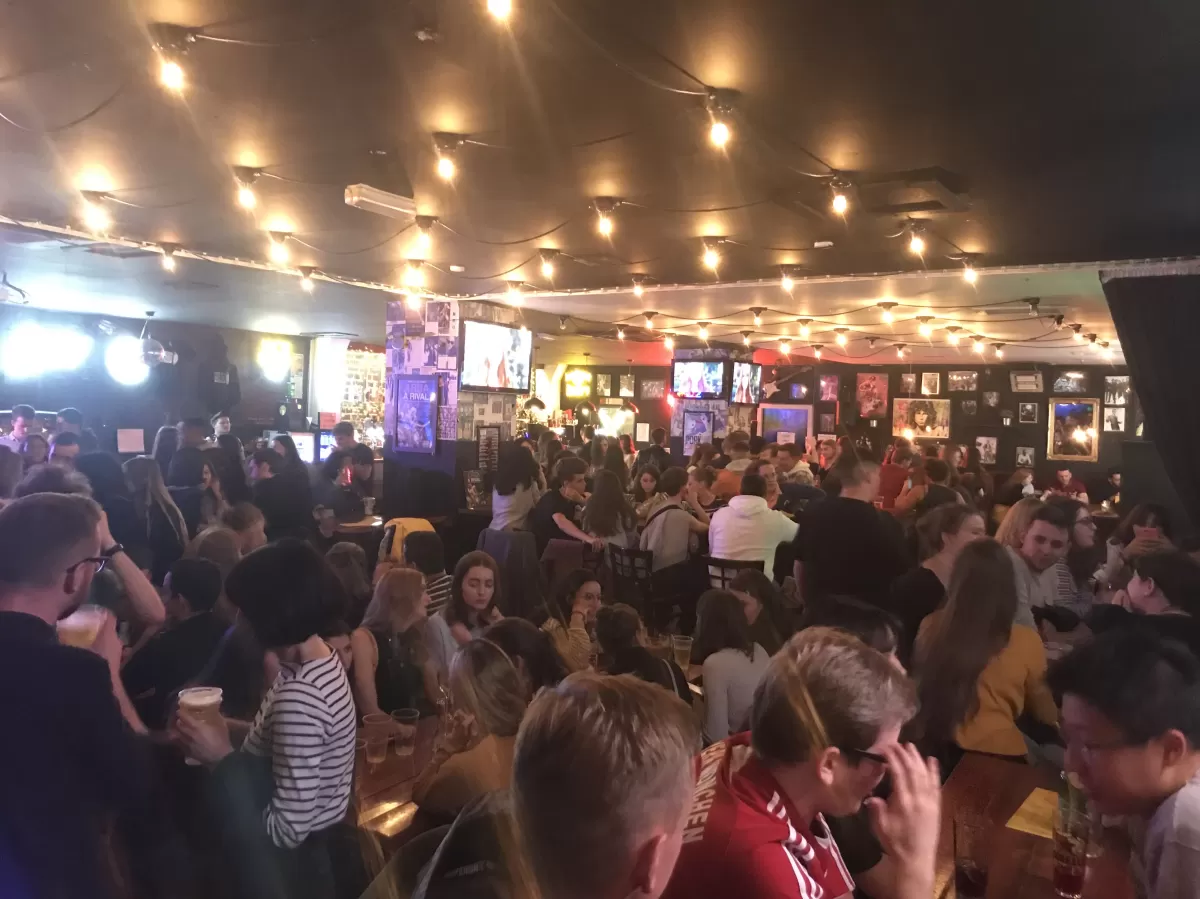 Image displays students socialising in a bar.