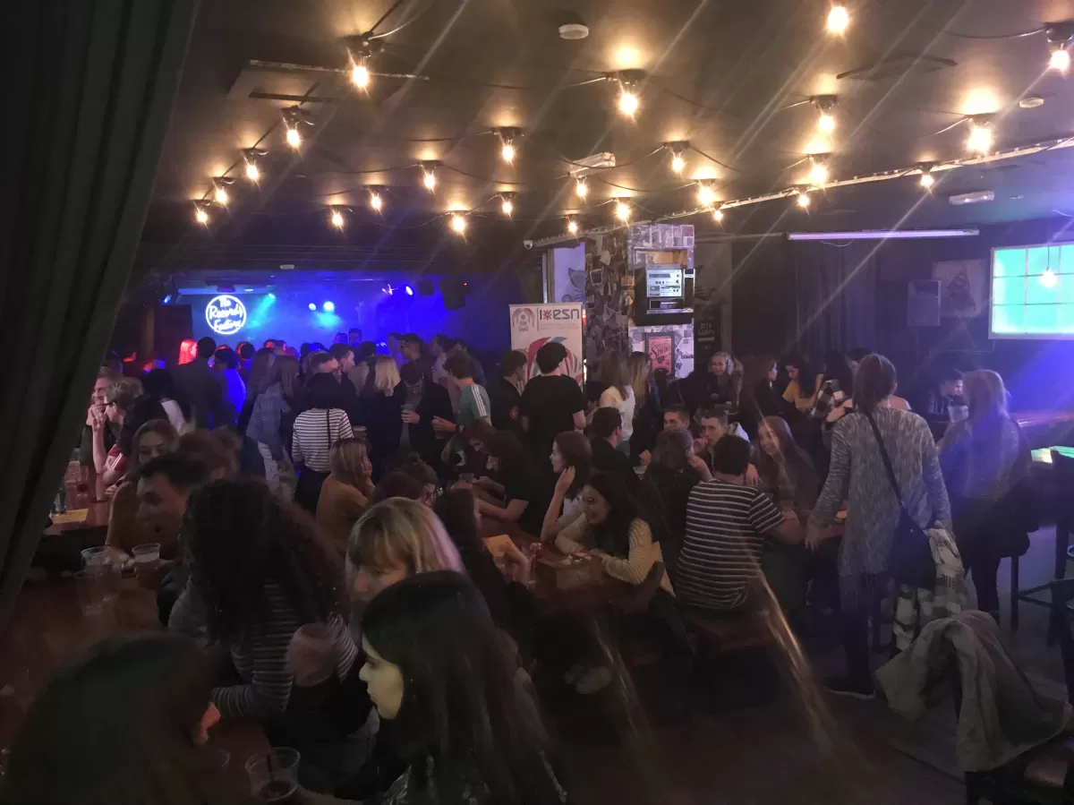 Image displays students socialising in a bar with our ESN banner in the background.