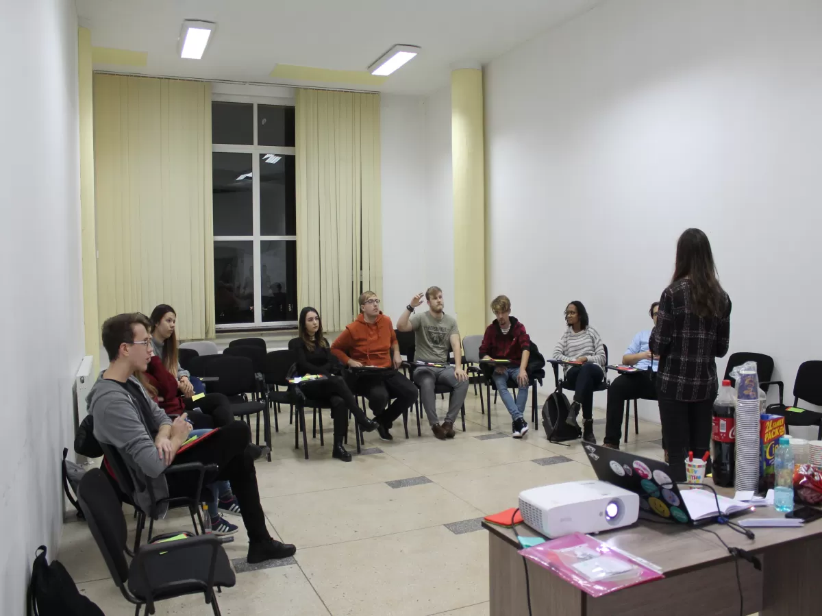 Students sitting in a semi-circle with a trainer standing in the center.