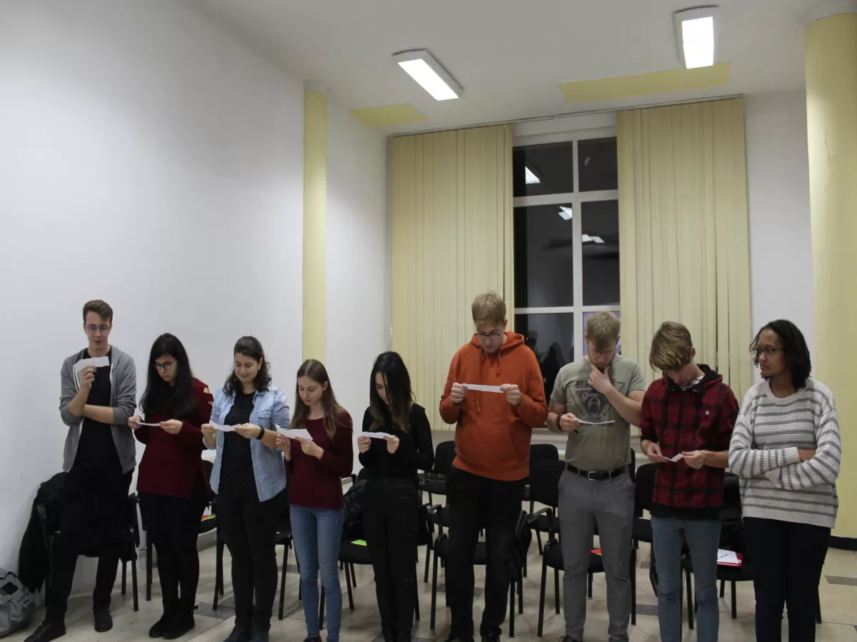 9 students standing in line next to each other in a classroom.