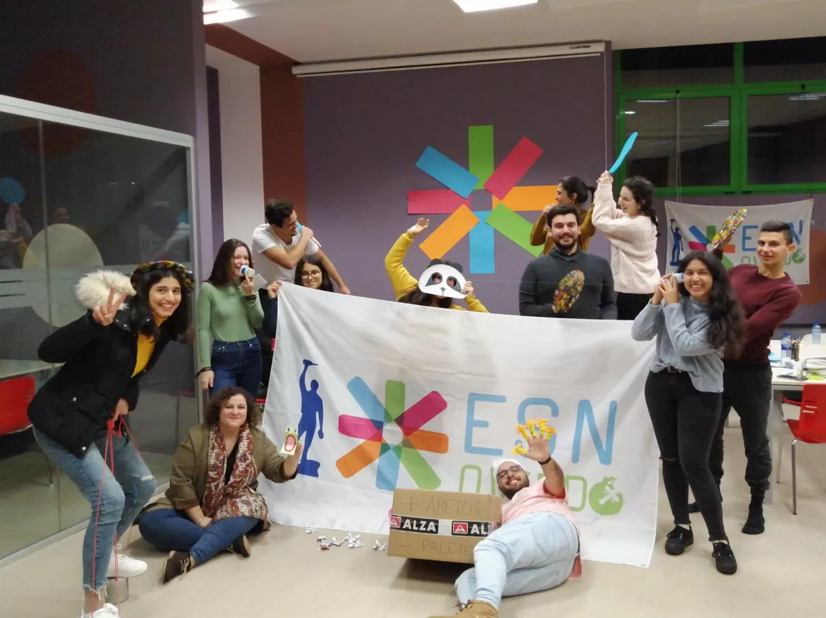 Several people posing with a flag and several hand-made crafts and toys