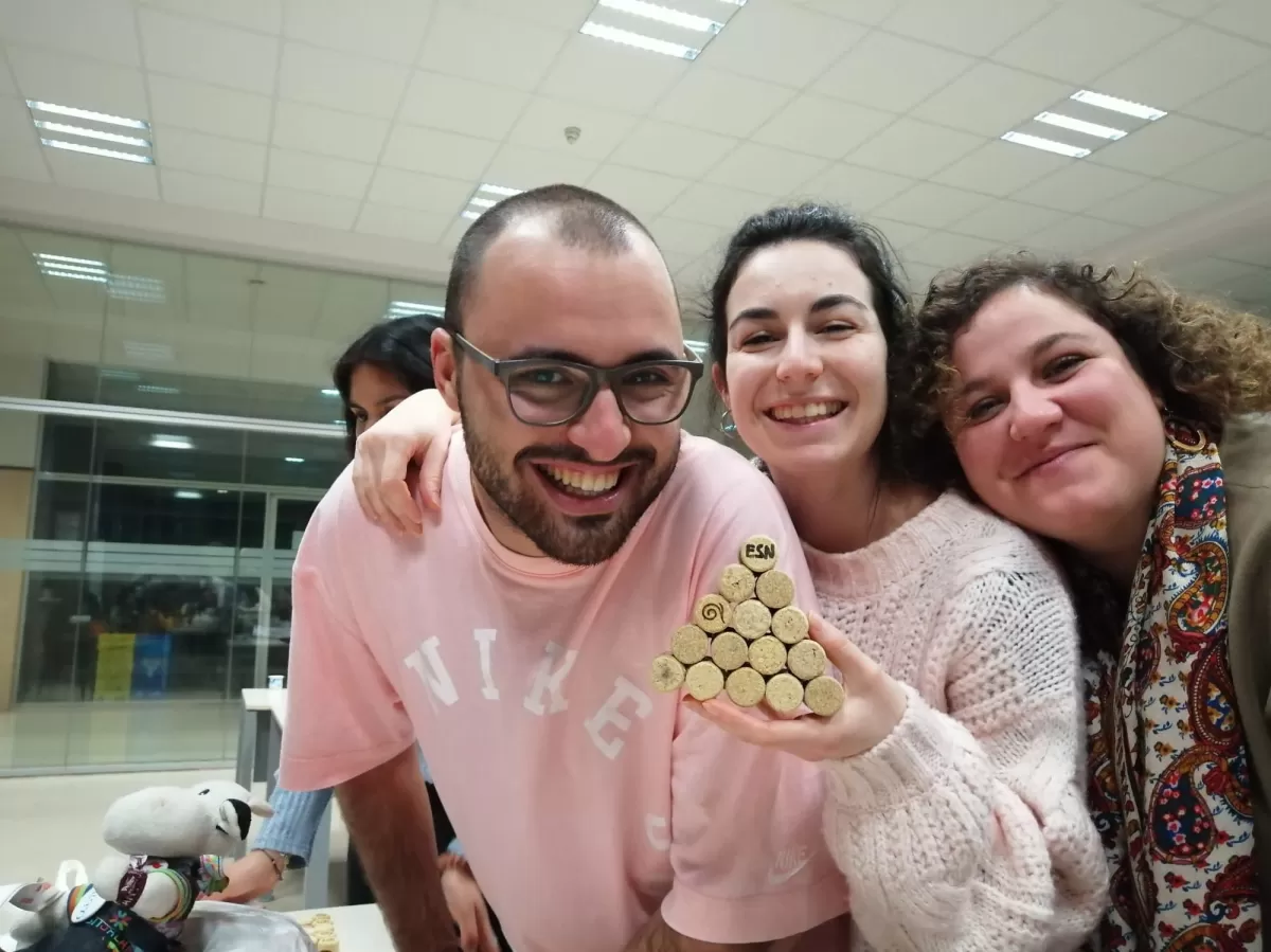 Three people pose smiling with a few bottle corks glued together