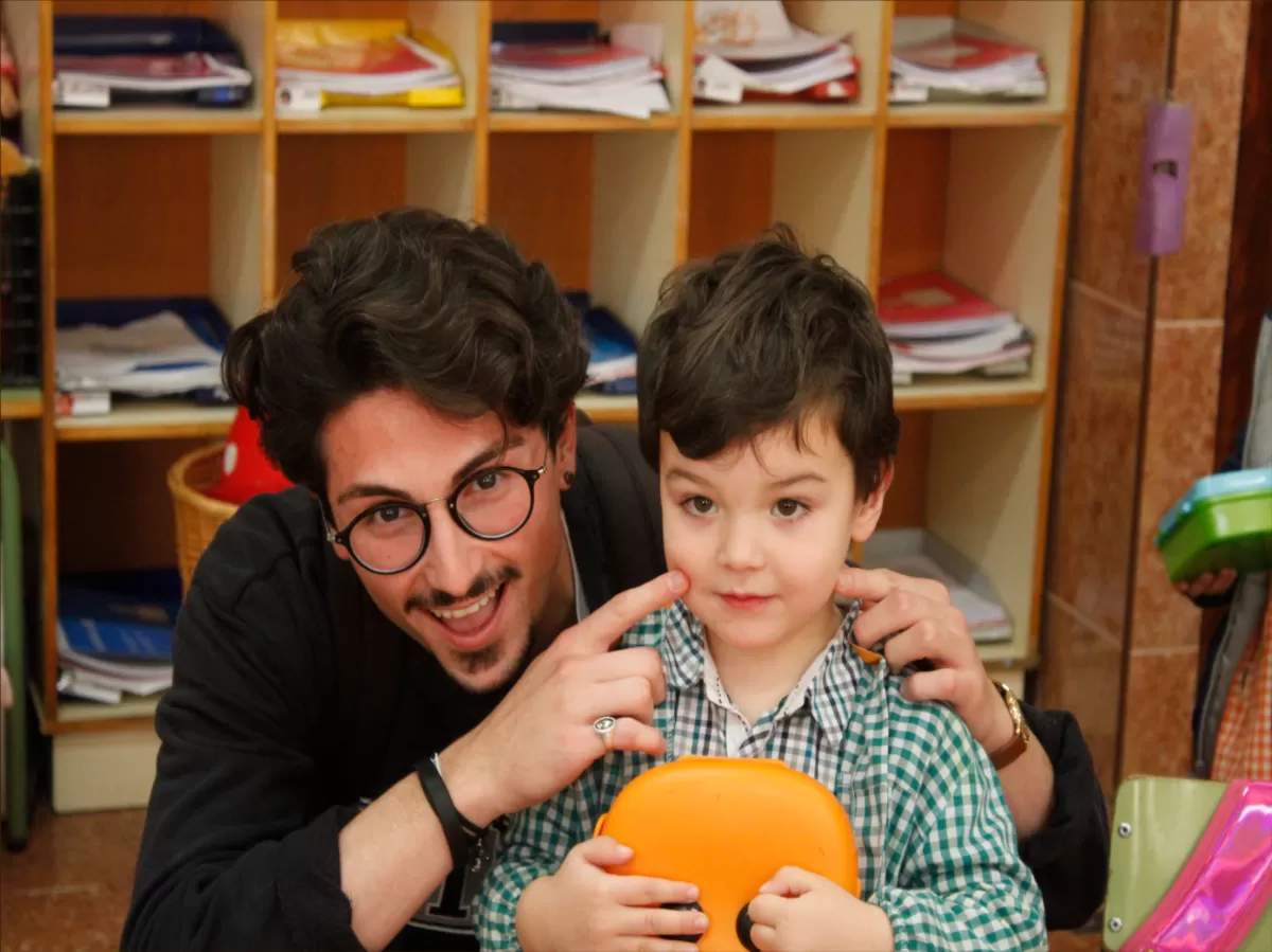 A young man with glasses plays with a kid