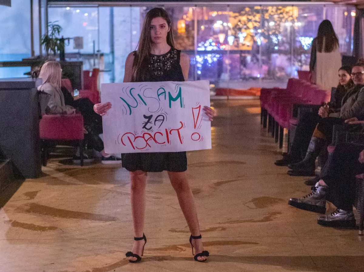 One of the models holding sign "Dont throw me away", wearing recycled dress.