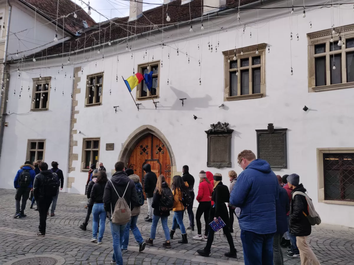 Group of people walking towards a building which has the Romanian and European flag.