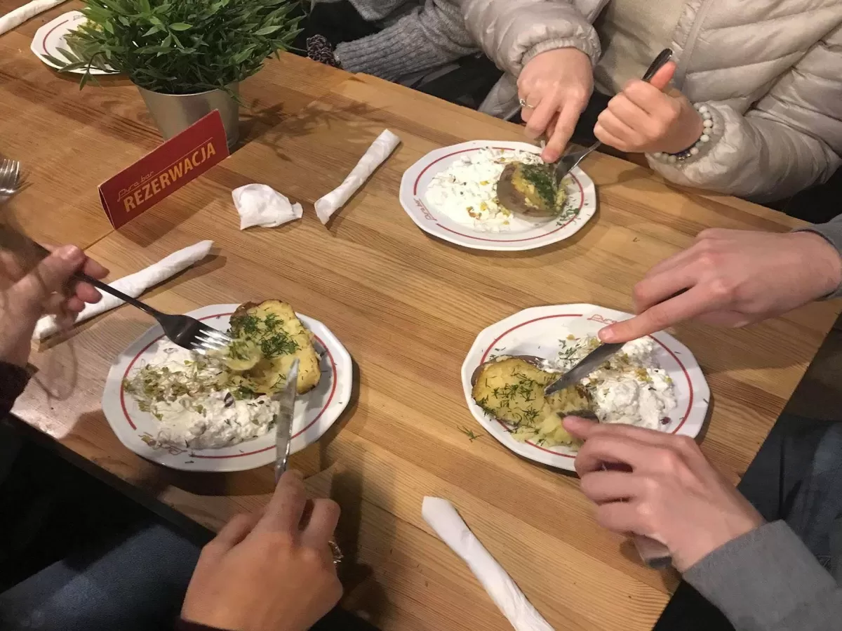 Three people eating "pyra z gzikiem", seen from above the table