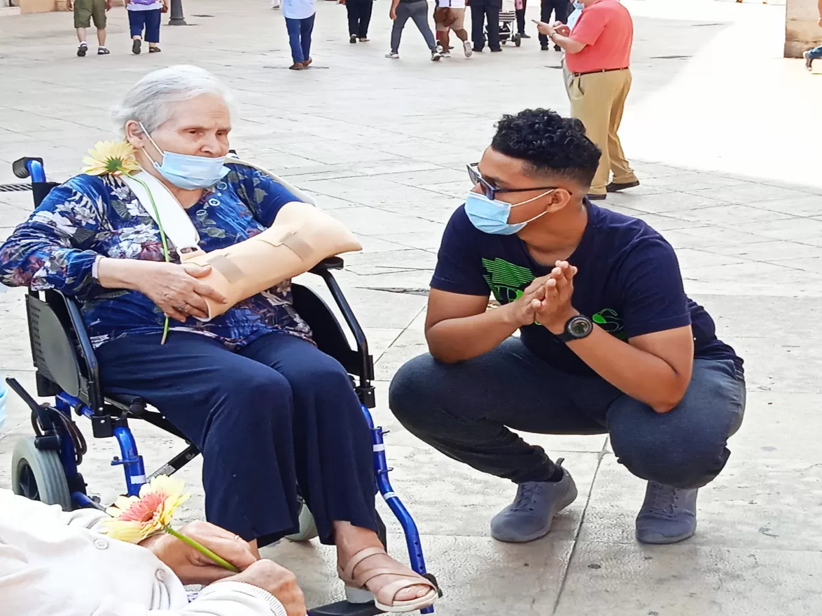 Volunteer giving a flower to an old person and discussing with her