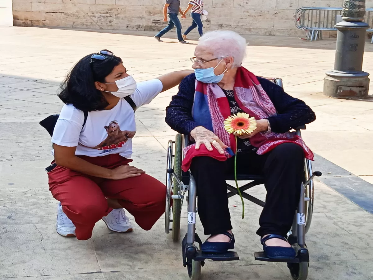 Volunteer giving a flower to an old person and discussing with her