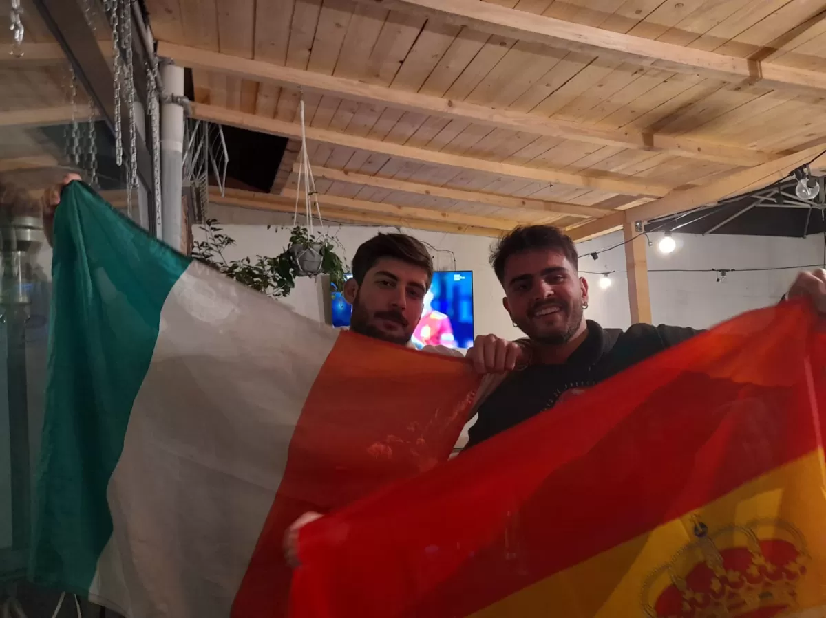a spanish and an italian guy posing with their country falg
