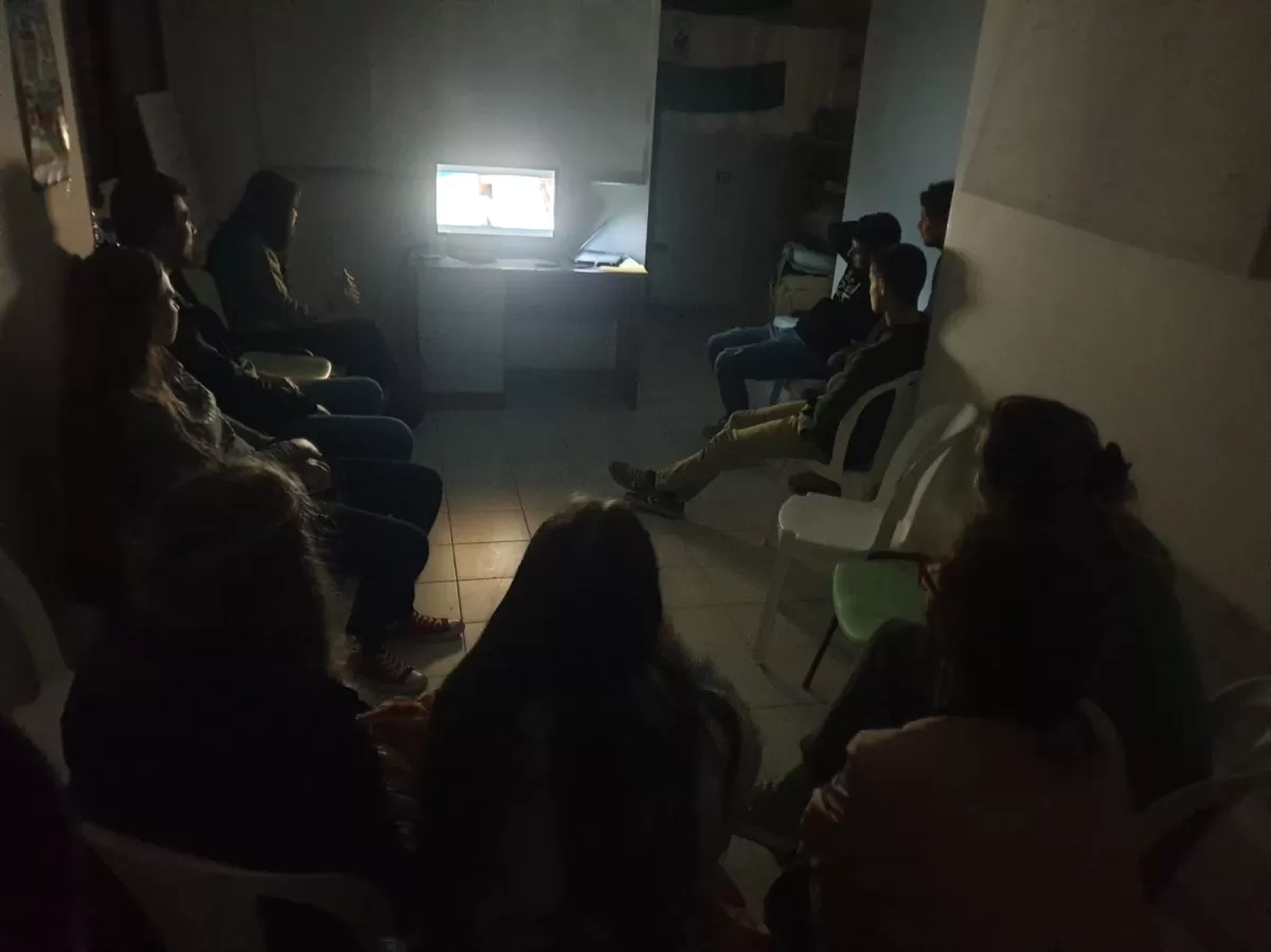 Group of students watching a documentary with the light off
