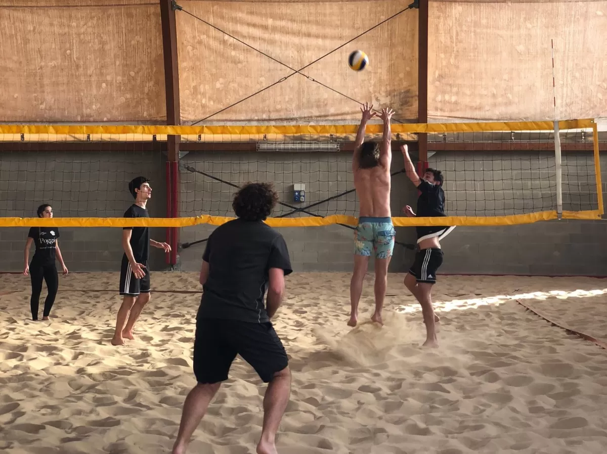 International students playing volleyball inside a gym