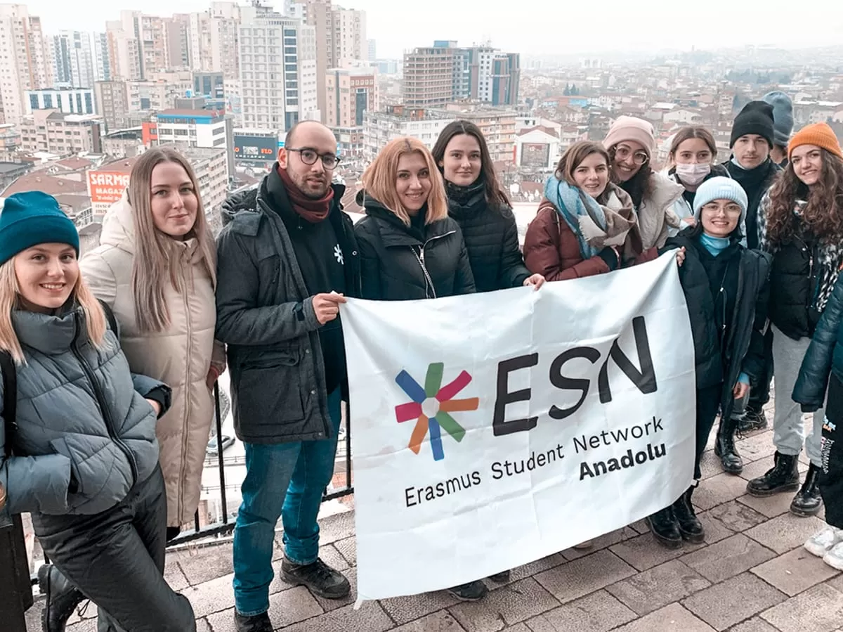 Participants smiling at the camera and holding the flag of ESN Anadolu with the background of the city from a high point