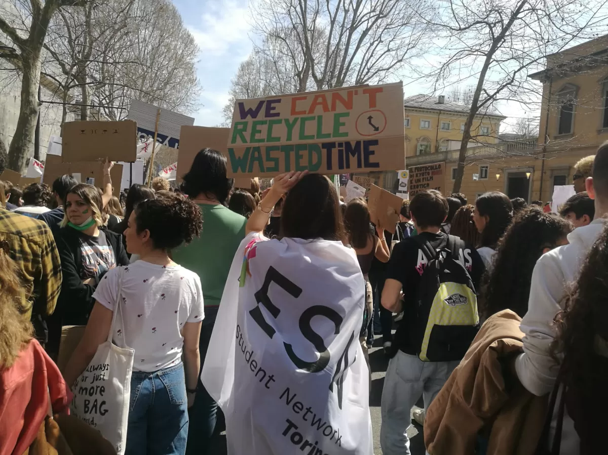 Photo of the parade. A person with the ESN Torino flag is showing a poster