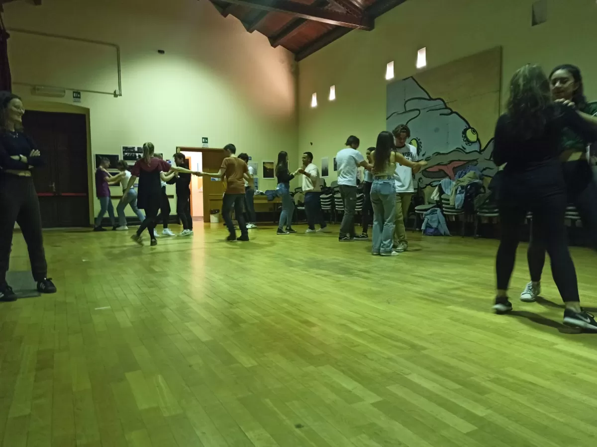 A group of international students and volunteers is dancing salsa in couples.