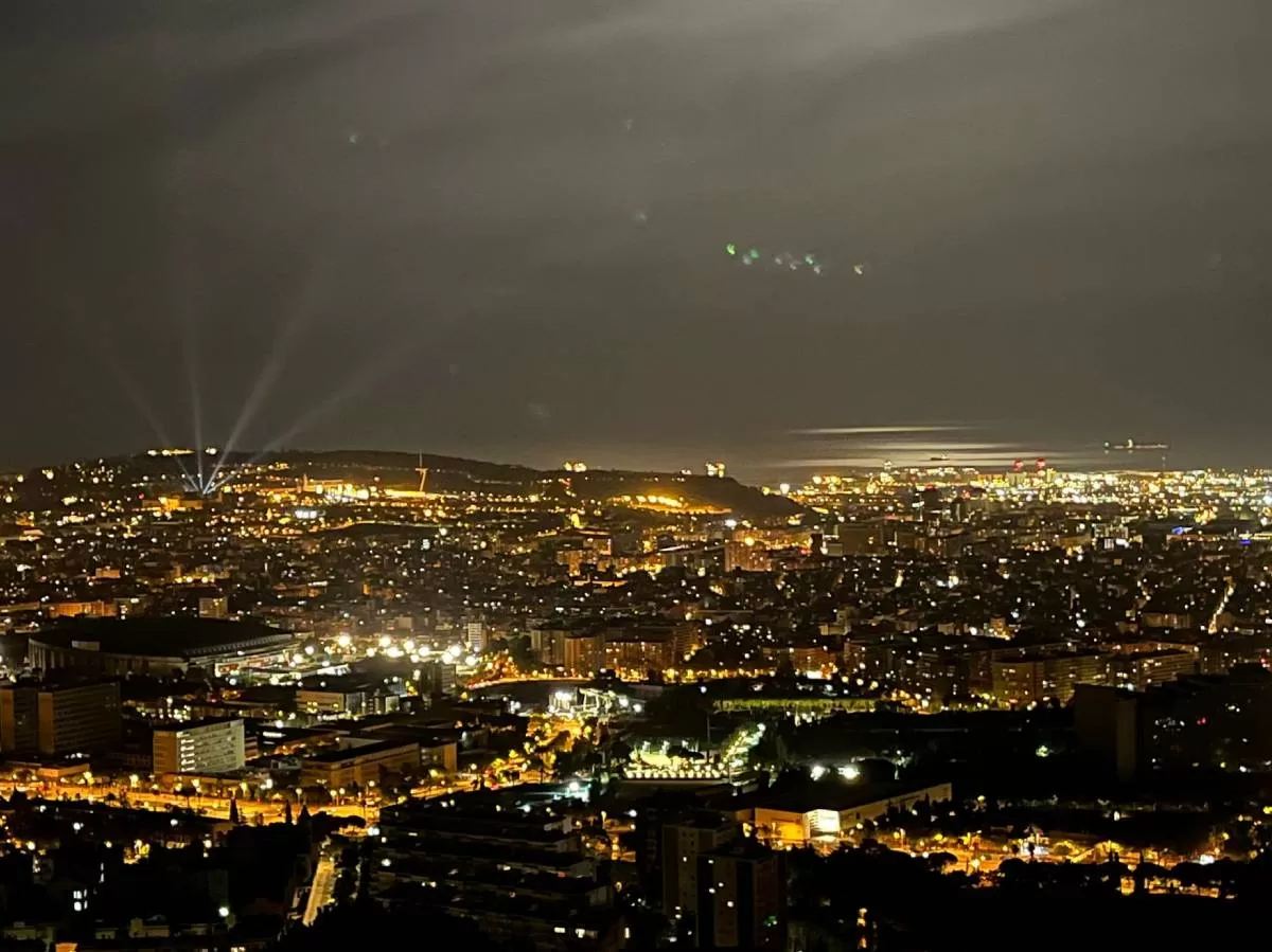 Skyline of Barcelona at night, with the lights of the buildings lighting up the city.