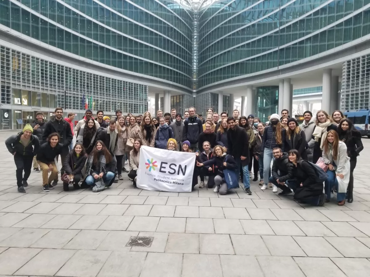 Group of international students and ESN volunteers posing with the flag in front the regional palace