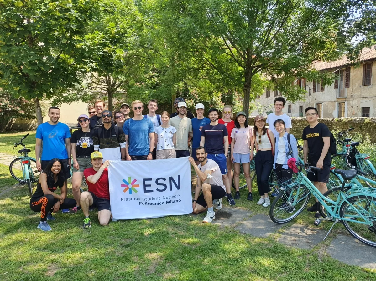 Group of international students and ESN volunteers posing with bikes and flag in a park