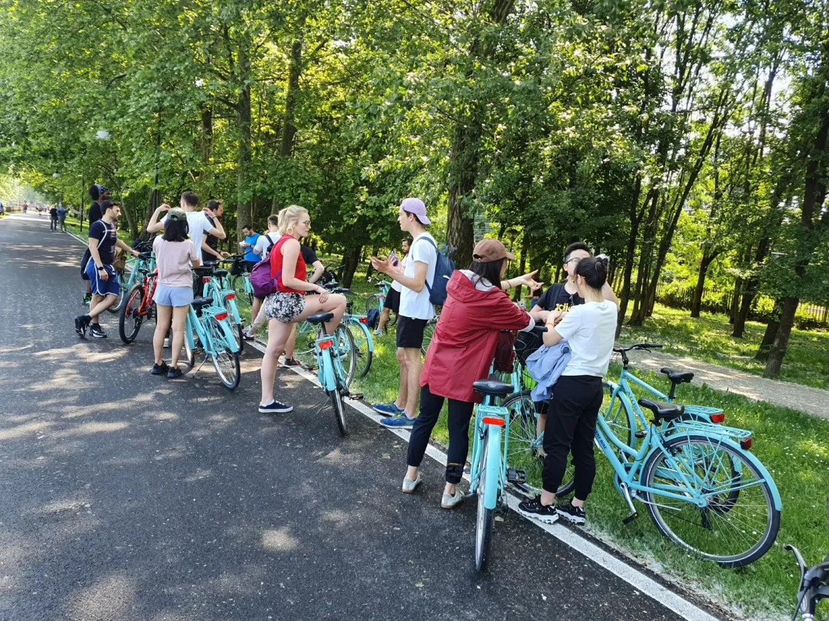 Group of international students resting with their bikes next to a park