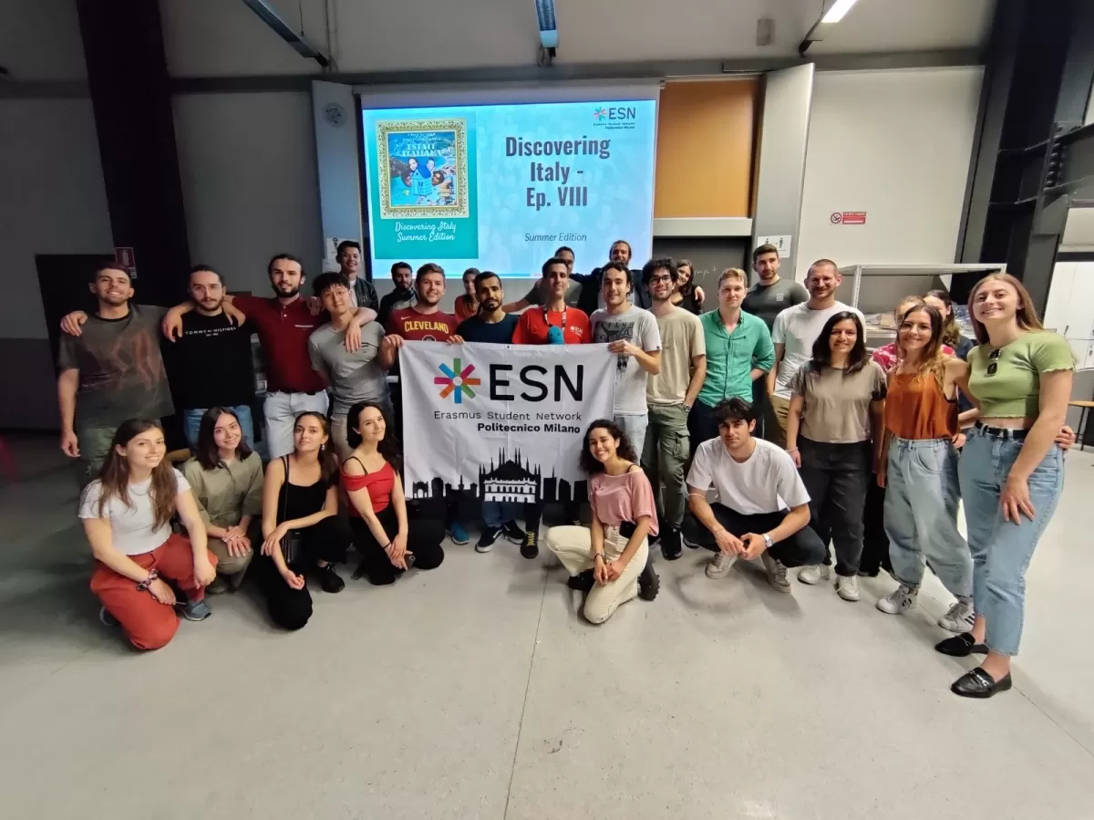 Group of international students and ESN volunteers posing with the flag in the classroom
