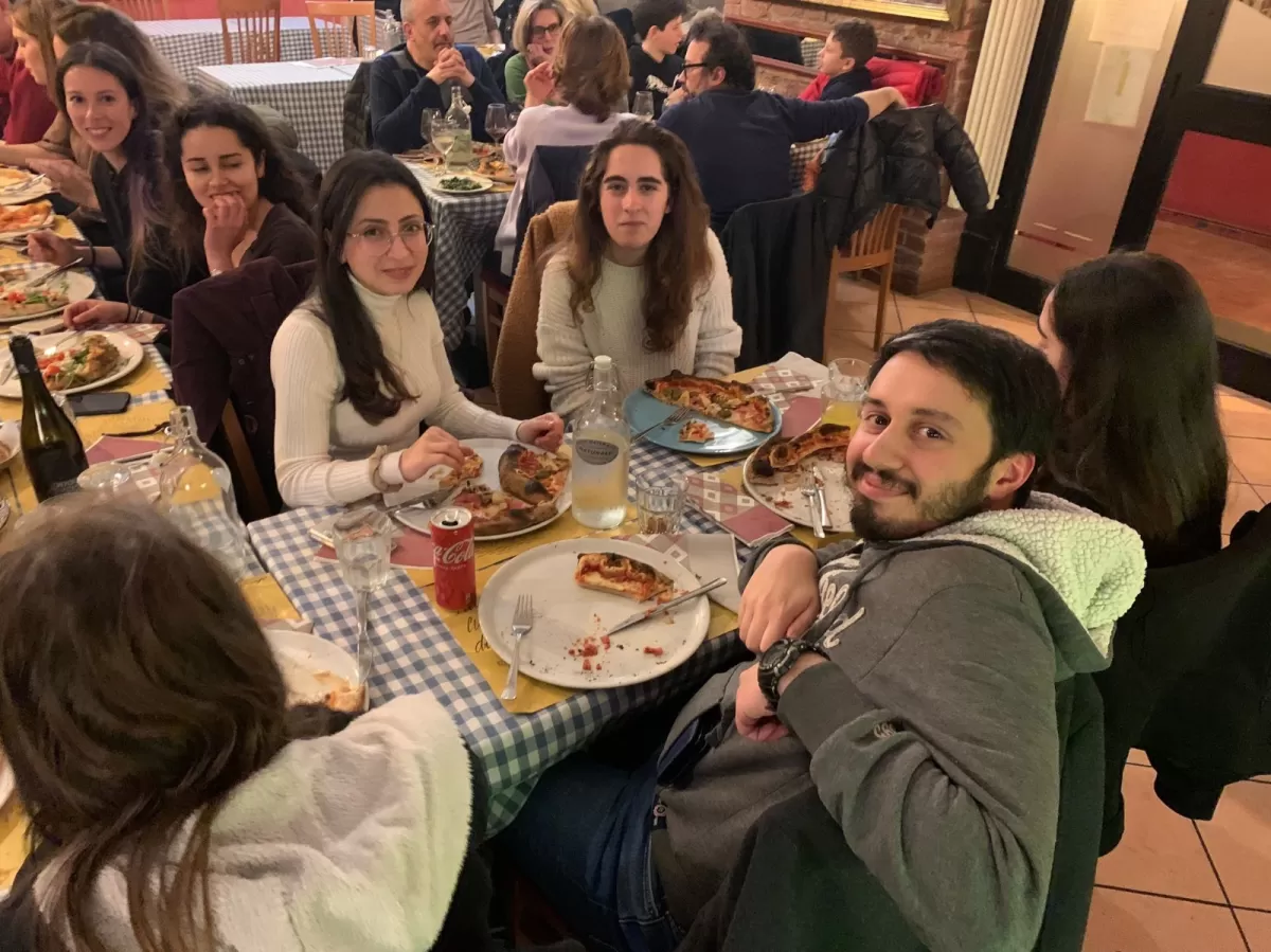 Group of international students sitting at the restaurant eating neapolitan pizza
