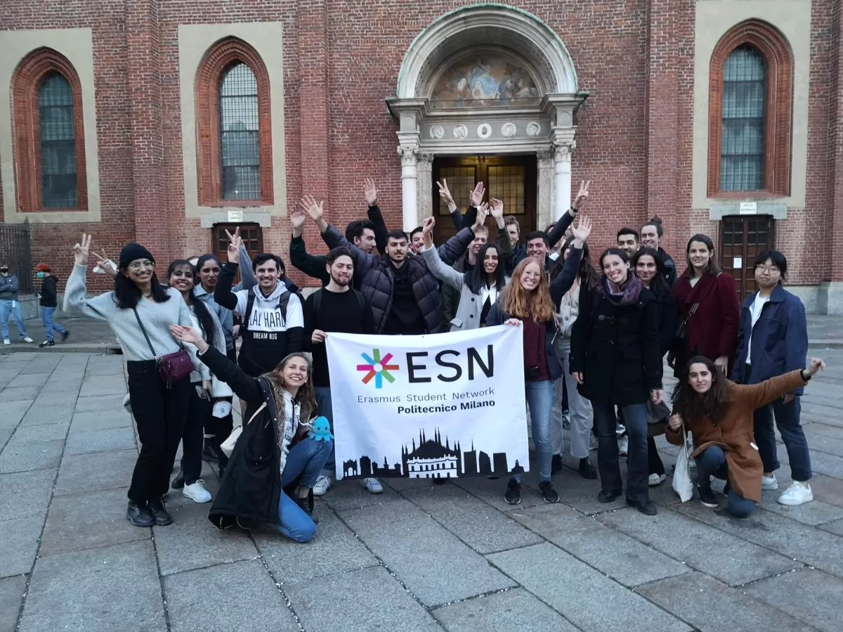 Group of international and ESN volunteers posing with the flag in front of the museum entrance