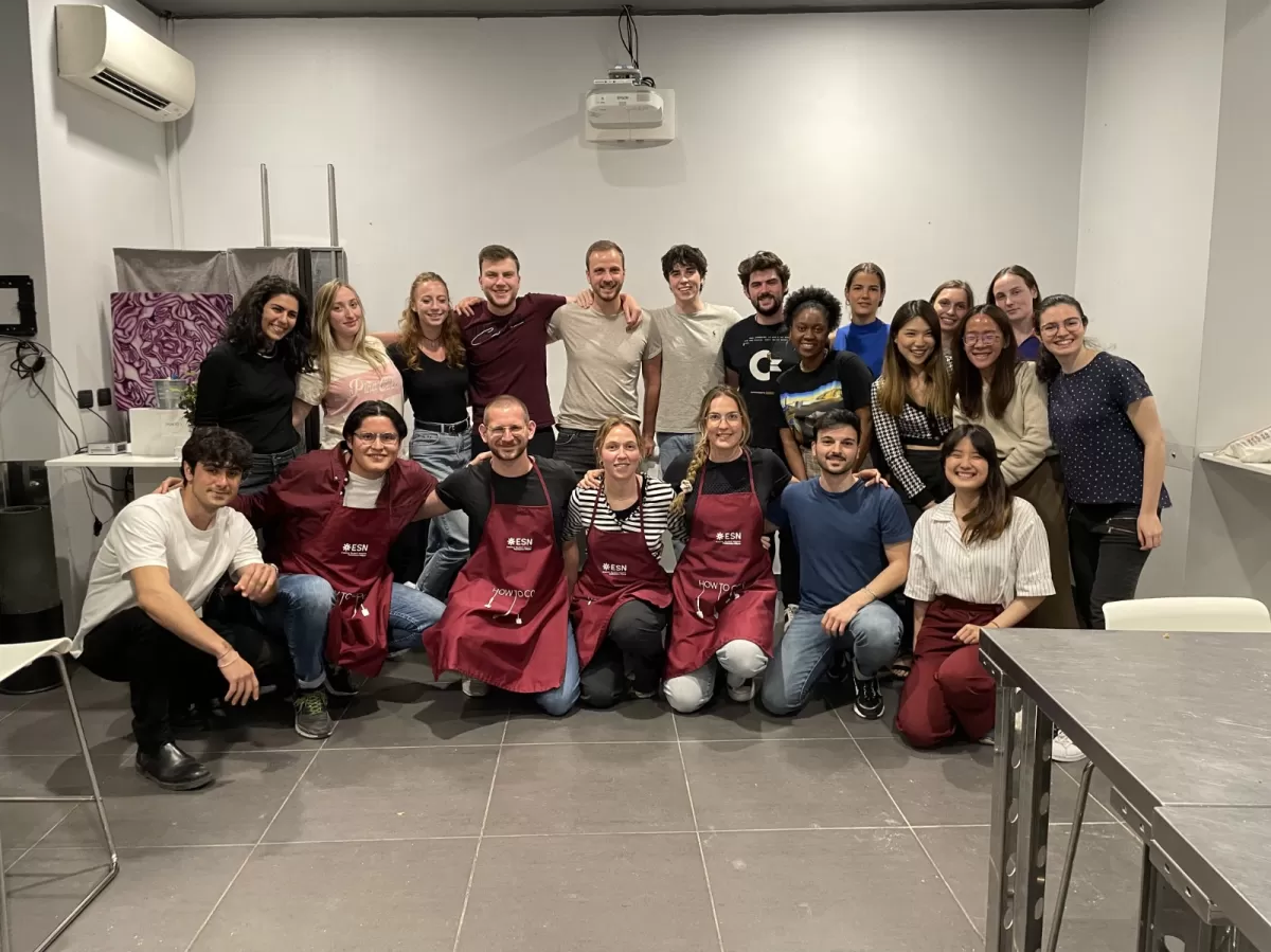 Group of international students and ESN volunteers posing with kitchen aprons