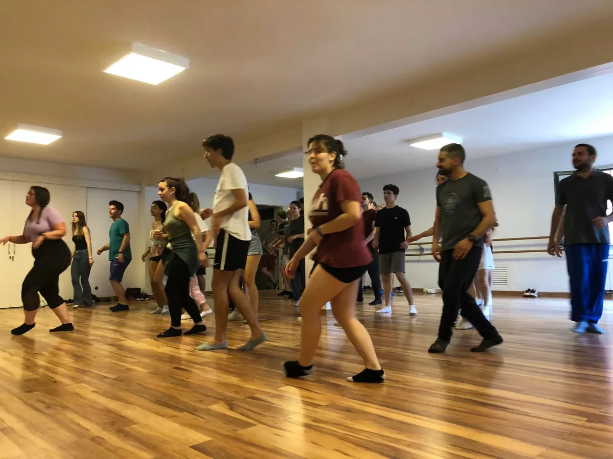Group of students dancing in a dance room. They are following the instructor's steps.