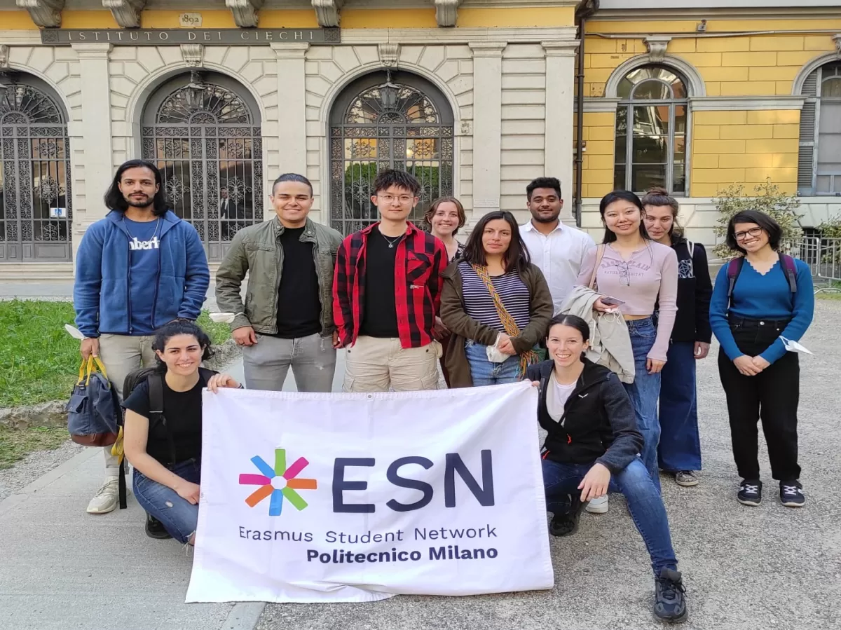 Group of international and ESN volunteers posing with the flag in front of blind people institute