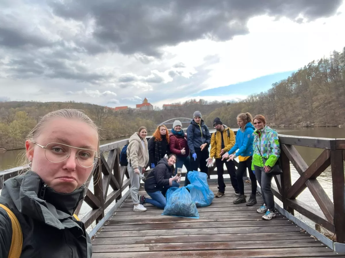 A group of students with collect trash with a Vevěří casle in the background