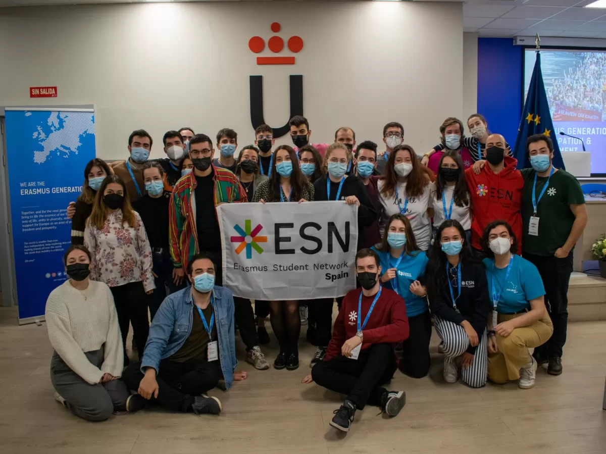 Group of young students and volunteers holding the ESN Spain flag.