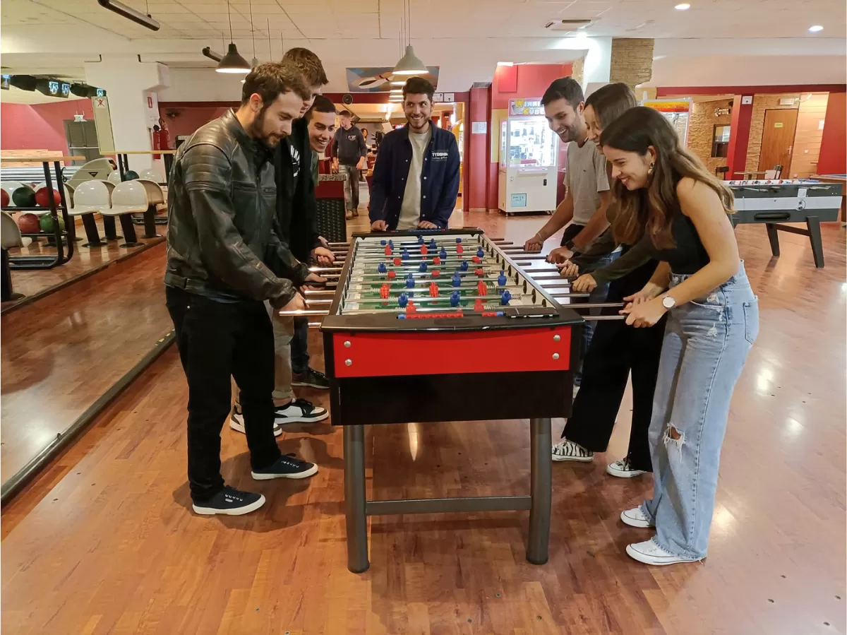A group of people are playing table football and laughing