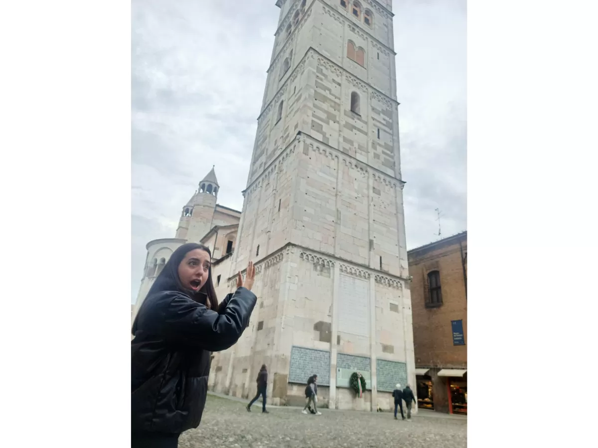 International student posing for a creative picture with Ghirlandina tower