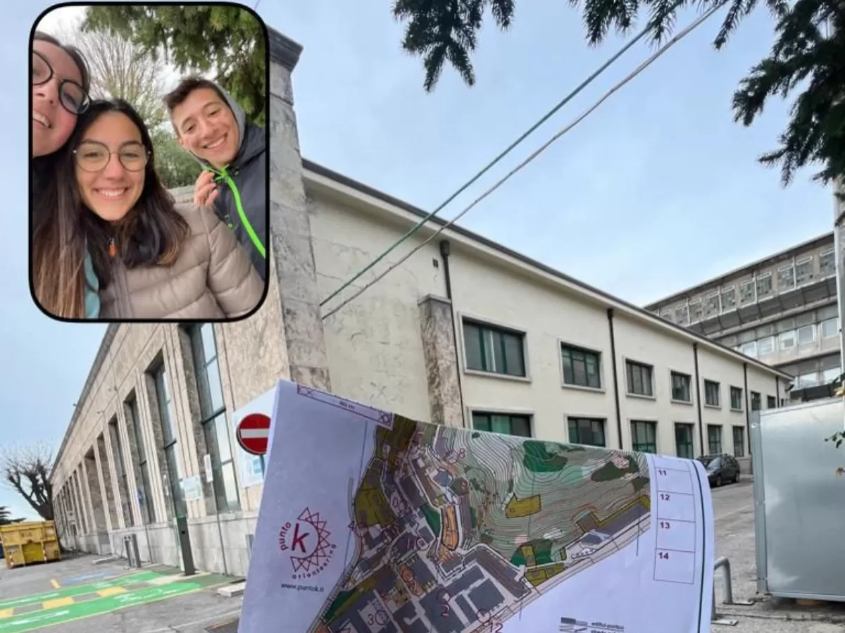 Picture taken via the BeReal of one of the participants. It shows three participants smiling and an orienteering map being held in front of a university building.