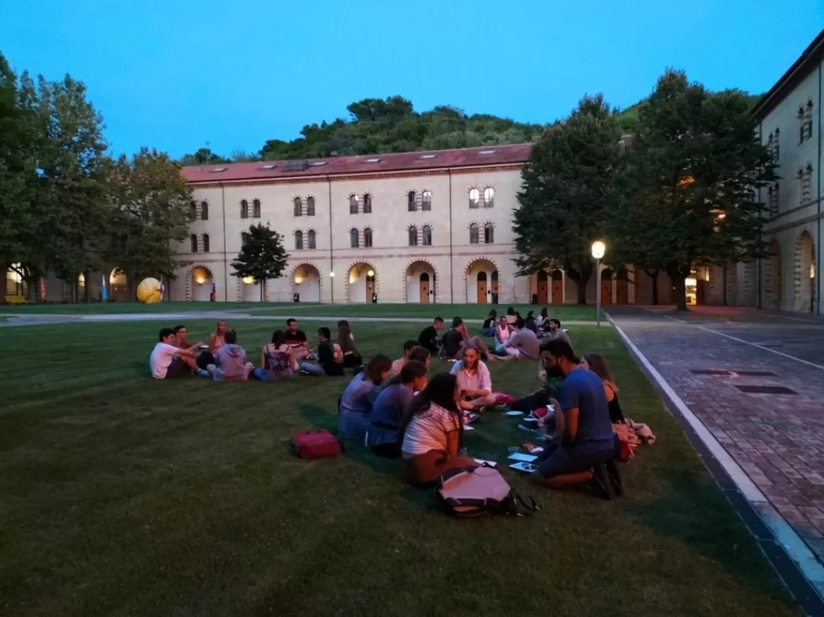 groups of people sitting on the grass in the courtyard of the university.
