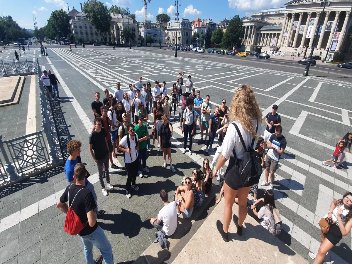 ESN BME mentor standing high and talking to Erasmus students at Heroes Square