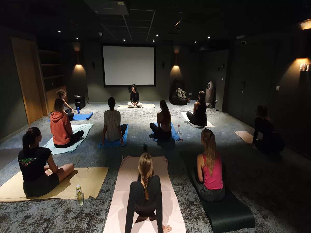 Erasmus students doing yoga in a dark, cozy room with carpeted floor