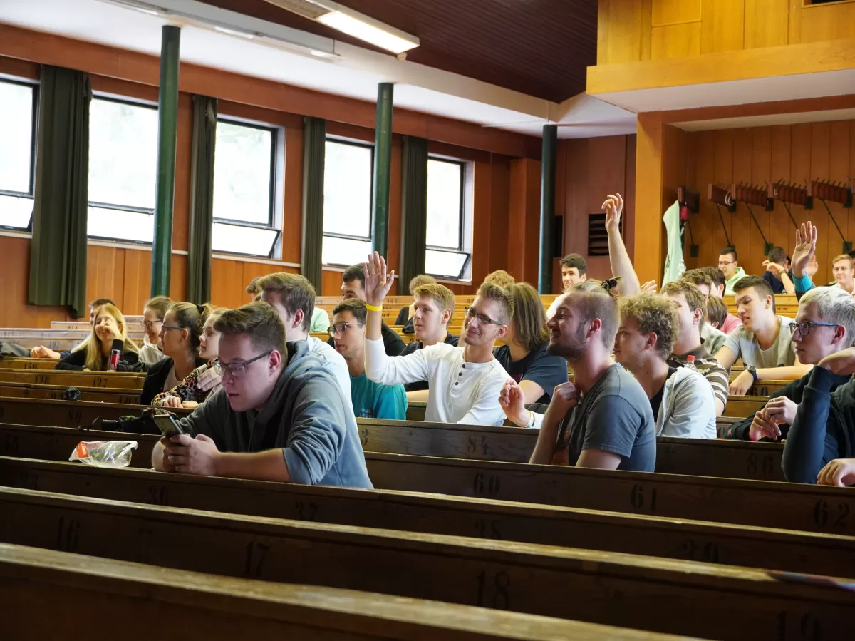 sitting students holding up their hands