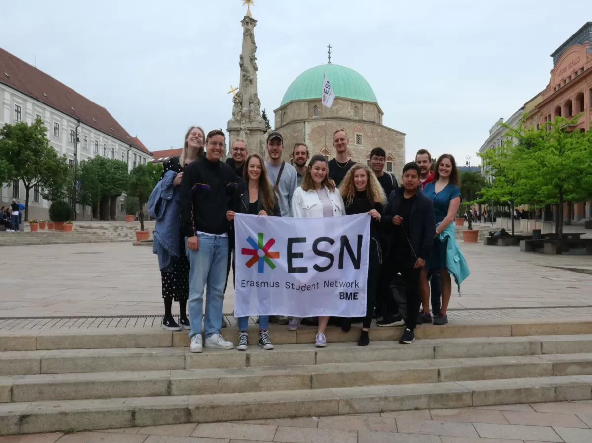 group photo with the Mosque of Pécs in the background and people holding the ESN BME flag