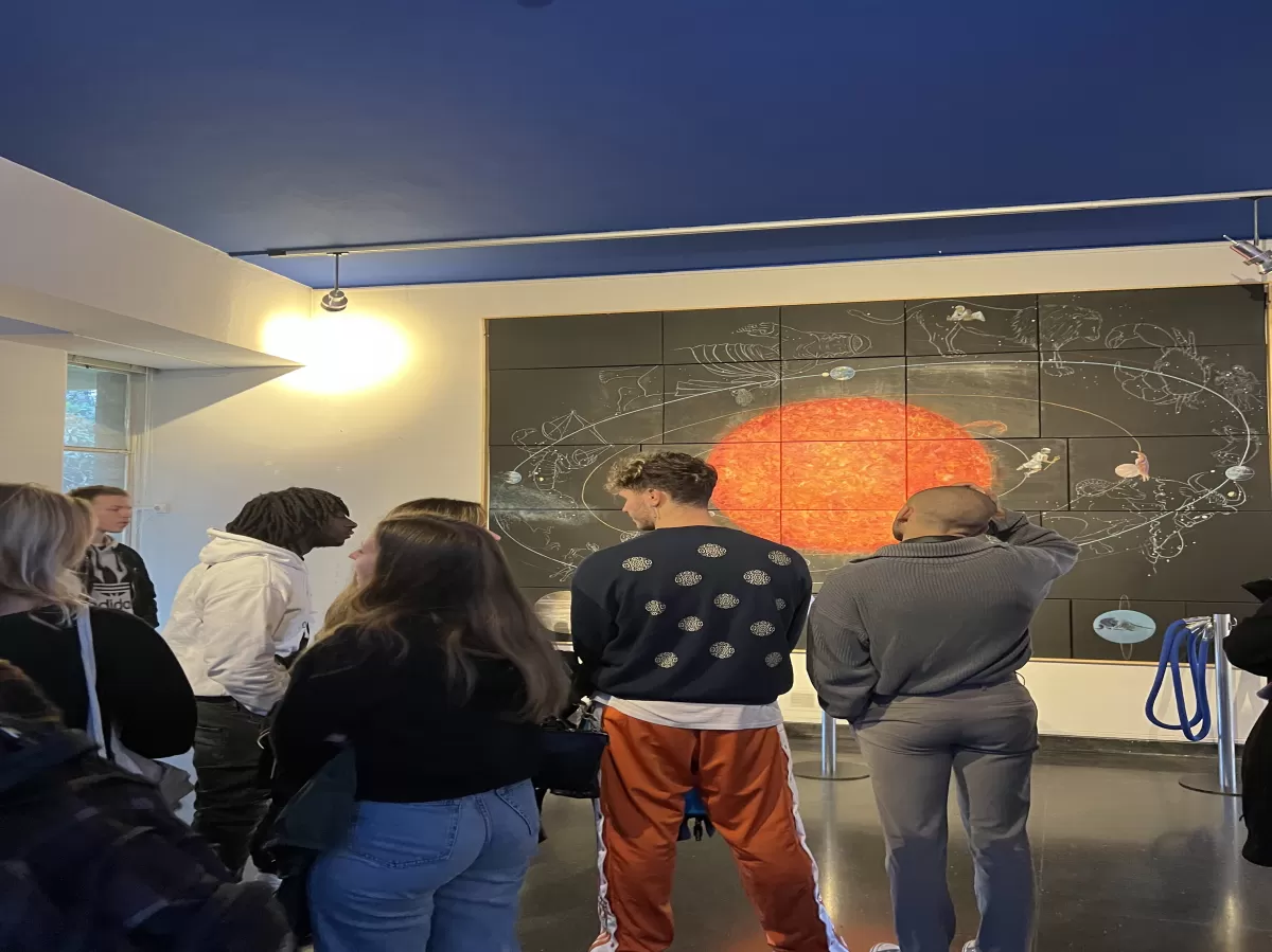 Back view of Erasmus students looking at a picture of the Solar System in the Museum