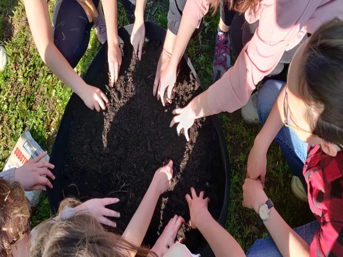 A group of people adjusting the soil in a raised garden bed.
