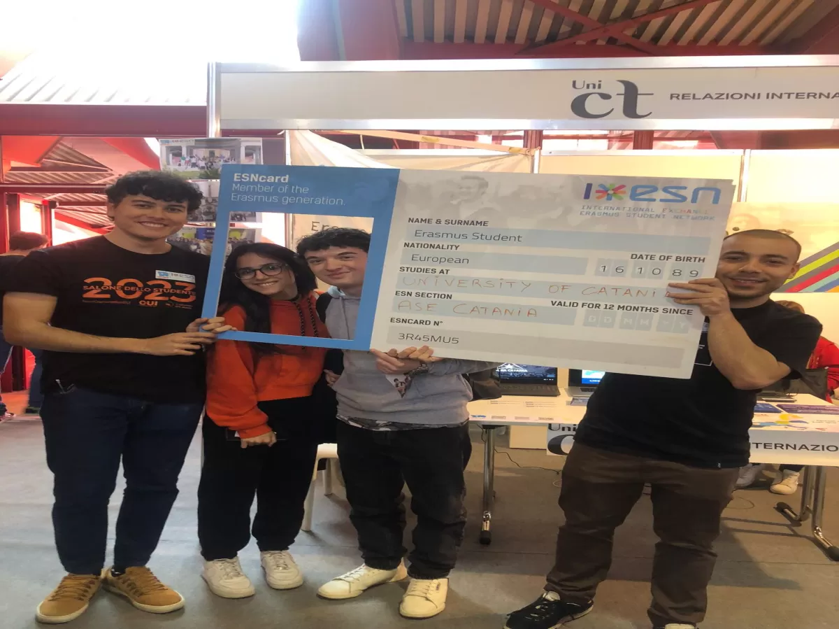 A volunteer and some high school students taking a picture with an ESN card poster