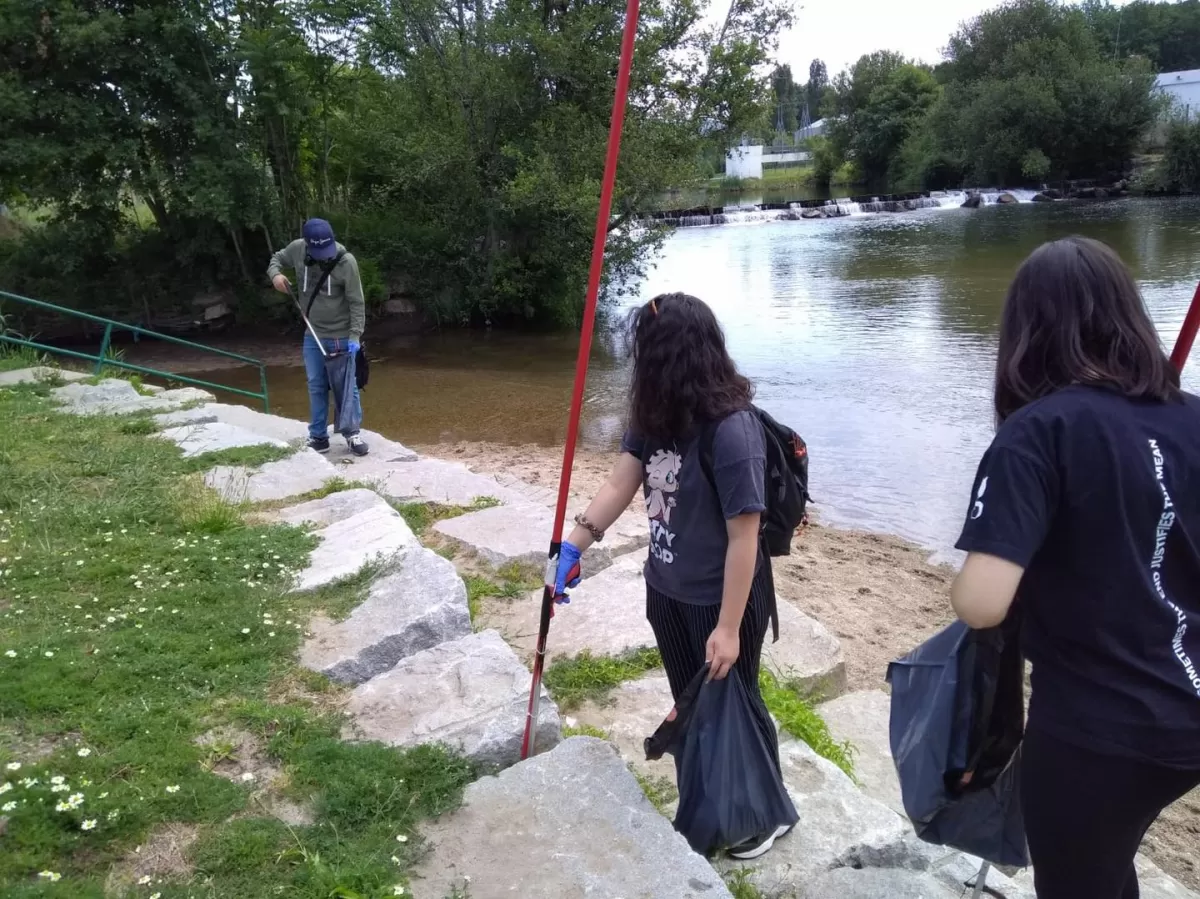 Participants near the shore of Ave River picking up trash.