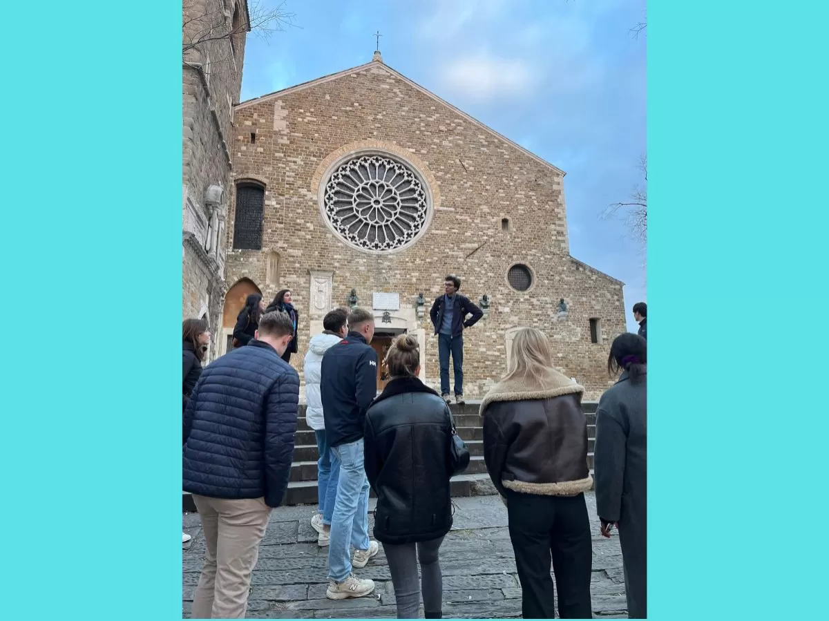 The participants are standing with their backs at the camera. In front of them is the cathedral of San Giusto.
