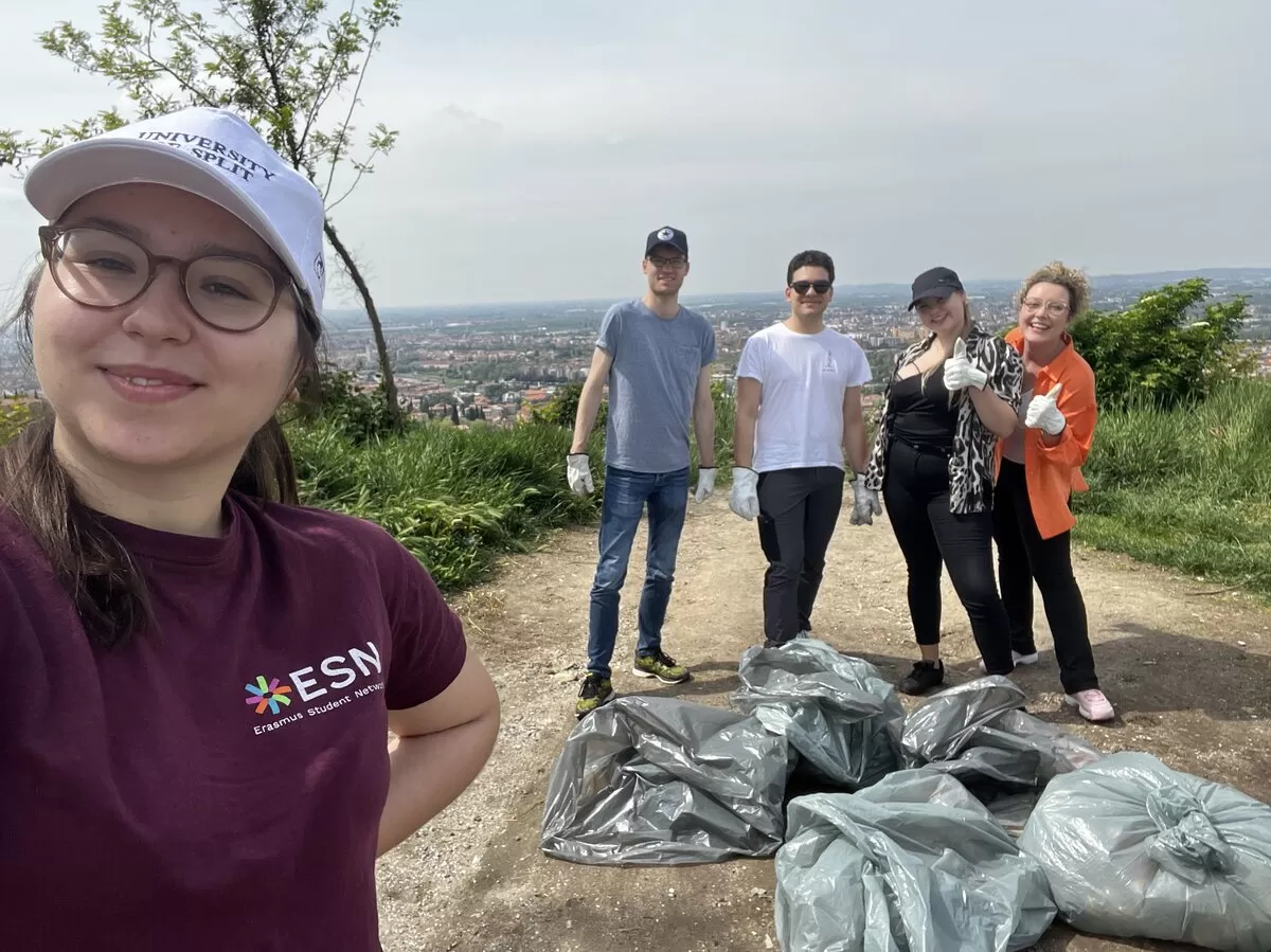 Group of international students cleaning up a green area of Verona from waste