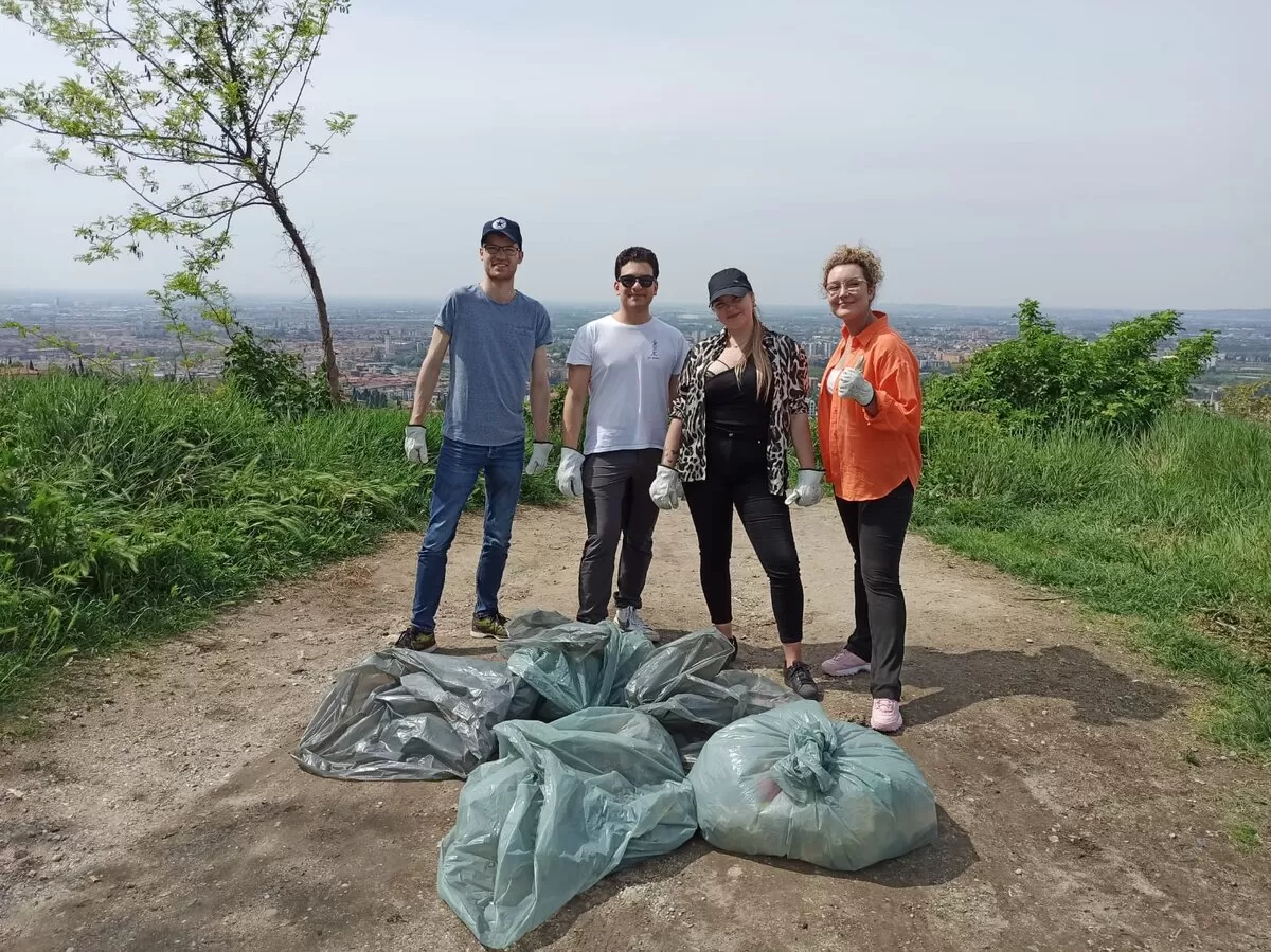 Group of international students cleaning up a green area of Verona from waste